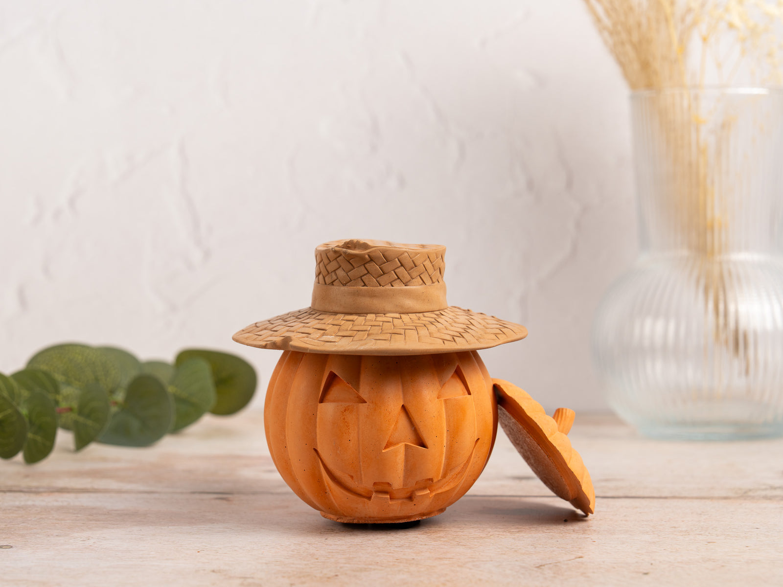 Concrete Carved pumpkin with a woven hat on a wooden surface