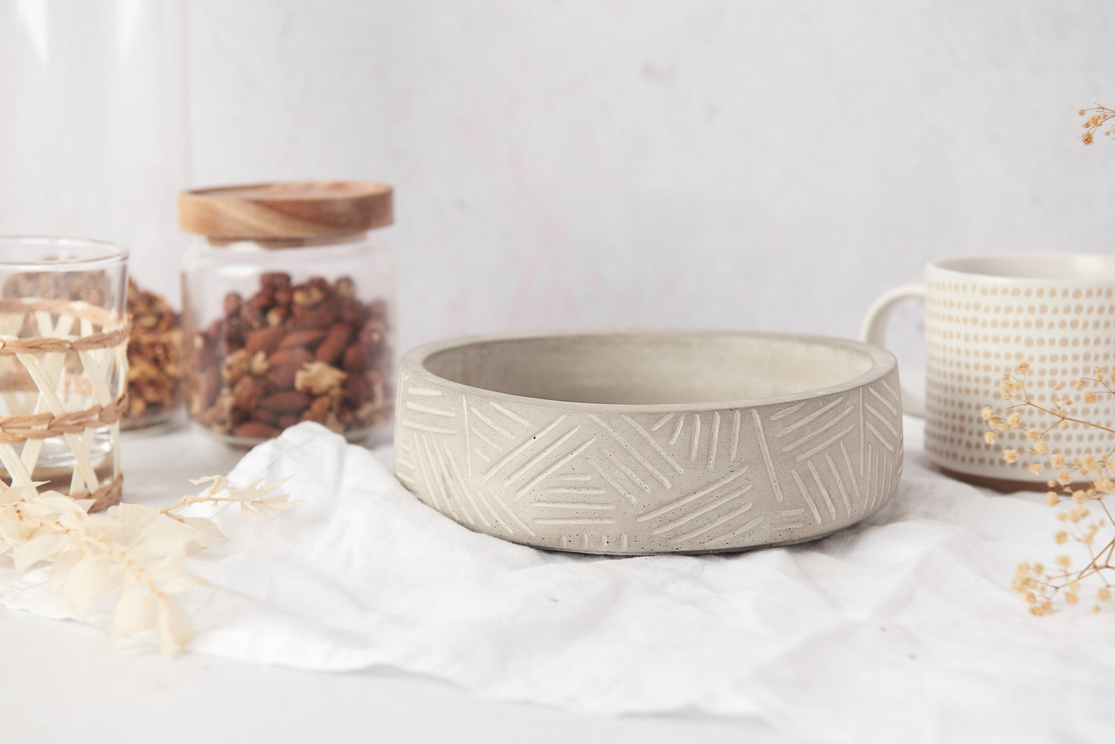 concrete bowl with textured design on a white surface with decorative items.